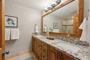 Bathroom with an enclosed shower, vanity, tile patterned floors, and a textured ceiling