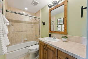 Full bathroom featuring bath / shower combo with glass door, vanity, a textured ceiling, tile patterned floors, and toilet