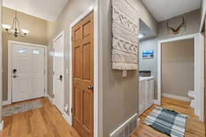 Foyer entrance featuring an inviting chandelier, washing machine and dryer, and light hardwood / wood-style flooring