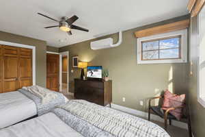 Bedroom featuring a wall unit AC, a closet, and ceiling fan