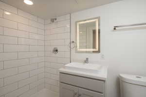 Bathroom with vanity, tiled shower, and toilet