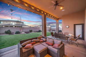 Patio terrace at dusk with ceiling fan, a yard, and outdoor lounge area