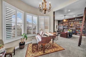 Carpeted office with an inviting chandelier and built in features