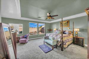 Carpeted bedroom with multiple windows, ceiling fan, crown molding, and a textured ceiling