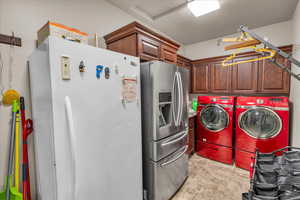 Clothes washing area with cabinets, washing machine and dryer, and a textured ceiling