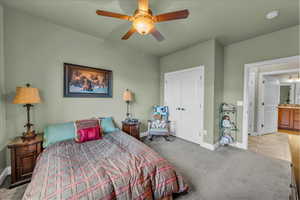 Carpeted bedroom featuring ceiling fan and a closet