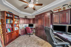 Home office with ceiling fan, a tray ceiling, built in desk, and light tile patterned floors