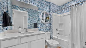 Full bathroom with shower / bath combo, vanity, and toilet