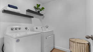 Laundry area with independent washer and dryer and light hardwood / wood-style floors