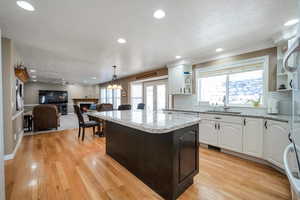 Kitchen featuring white cabinetry, sink, light hardwood / wood-style flooring, and pendant lighting