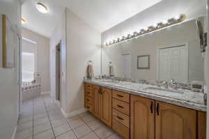 Primary bathroom featuring vanity, tile patterned flooring, and vaulted ceiling