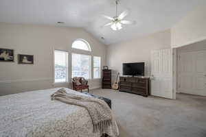 Primary bedroom featuring lofted ceiling, light carpet, and ceiling fan