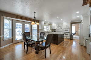 Dining area with crown molding, sink, light hardwood / wood-style flooring, and a textured ceiling