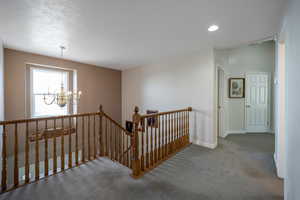 Staircase with carpet, a textured ceiling, and a chandelier