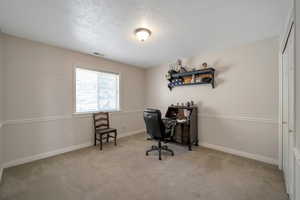 Carpeted office with a textured ceiling