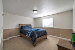 Bedroom with light colored carpet and a textured ceiling