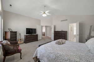 Carpeted primary bedroom featuring high vaulted ceiling, ceiling fan, and ensuite bath