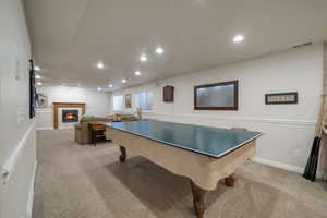 Recreation room featuring a tiled fireplace and light carpet