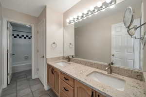 Bathroom with vanity, tile patterned floors, and tiled shower / bath