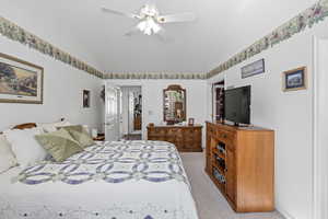 Bedroom featuring vaulted ceiling, light colored carpet, and ceiling fan