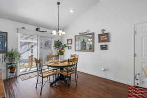 Dining space featuring an inviting chandelier, lofted ceiling, and dark hardwood / wood-style flooring