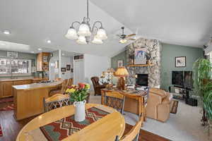 Dining room with dark hardwood / wood-style floors, a fireplace, lofted ceiling, sink, and ceiling fan