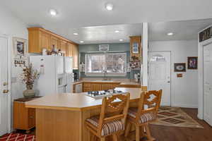 Kitchen featuring sink, a textured ceiling, dark hardwood / wood-style flooring, kitchen peninsula, and white appliances