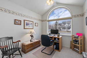 Carpeted office space with ceiling fan, vaulted ceiling, and a healthy amount of sunlight