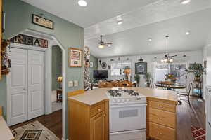 Kitchen with dark hardwood / wood-style flooring, lofted ceiling with beams, a textured ceiling, white range with gas cooktop, and ceiling fan with notable chandelier