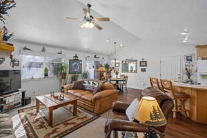 Living room featuring ceiling fan, vaulted ceiling, dark hardwood / wood-style floors, and a textured ceiling