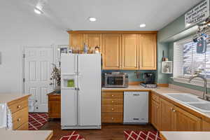 Kitchen featuring white appliances, dark hardwood / wood-style floors, sink, and a textured ceiling