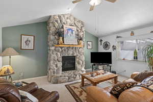 Carpeted living room featuring ceiling fan, a fireplace, vaulted ceiling, and a textured ceiling