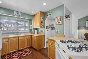 Kitchen with lofted ceiling, sink, gas range gas stove, a textured ceiling, and dark hardwood / wood-style flooring