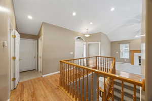 Hallway featuring vaulted ceiling and light hardwood / wood-style flooring