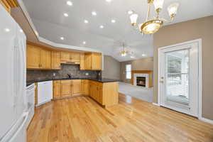 Kitchen featuring ceiling fan with notable chandelier, sink, hanging light fixtures, kitchen peninsula, and white appliances