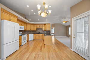 Kitchen with hanging light fixtures, vaulted ceiling, sink, and white appliances