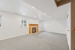 Unfurnished living room with a tile fireplace, carpet flooring, and a textured ceiling