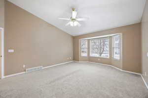 Carpeted empty room featuring vaulted ceiling and ceiling fan