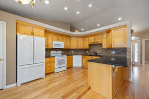 Kitchen featuring white appliances, lofted ceiling, light hardwood / wood-style floors, and sink