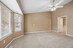 Empty room with lofted ceiling, light carpet, and ceiling fan