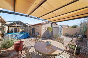 View of patio / terrace with a fenced in pool and a storage unit