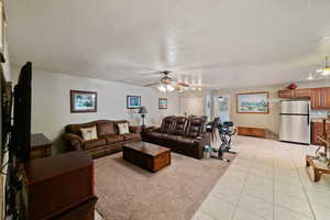 Tiled living room with ceiling fan and a textured ceiling