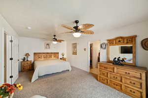 Bedroom with a walk in closet, light carpet, a textured ceiling, and ceiling fan