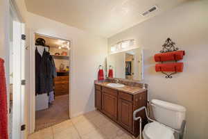 Bathroom featuring vanity, tile patterned flooring, a textured ceiling, and toilet