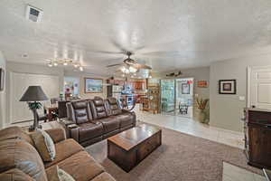 Tiled living room featuring ceiling fan and a textured ceiling