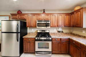 Kitchen featuring light stone counters, light tile patterned floors, and appliances with stainless steel finishes