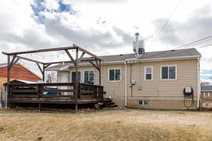 Rear view of property featuring a wooden deck and a lawn