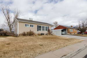 Ranch-style house featuring a carport and a front lawn