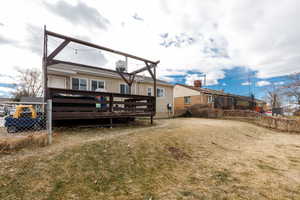 Back of house featuring a wooden deck and a lawn