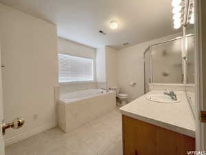 Full bathroom featuring vanity, toilet, separate shower and tub, and tile patterned flooring